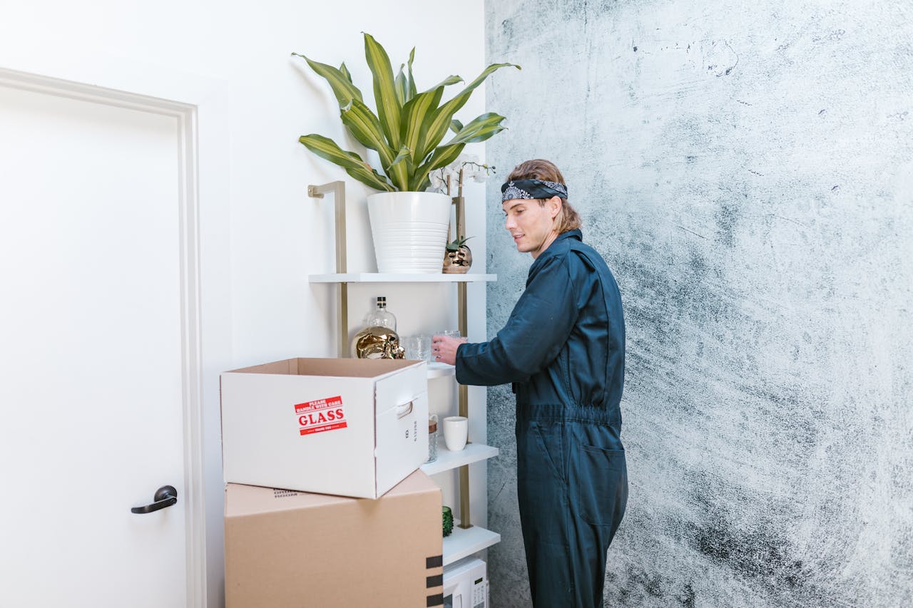 journey Man in uniform arranging home items with cardboard boxes ready for moving.